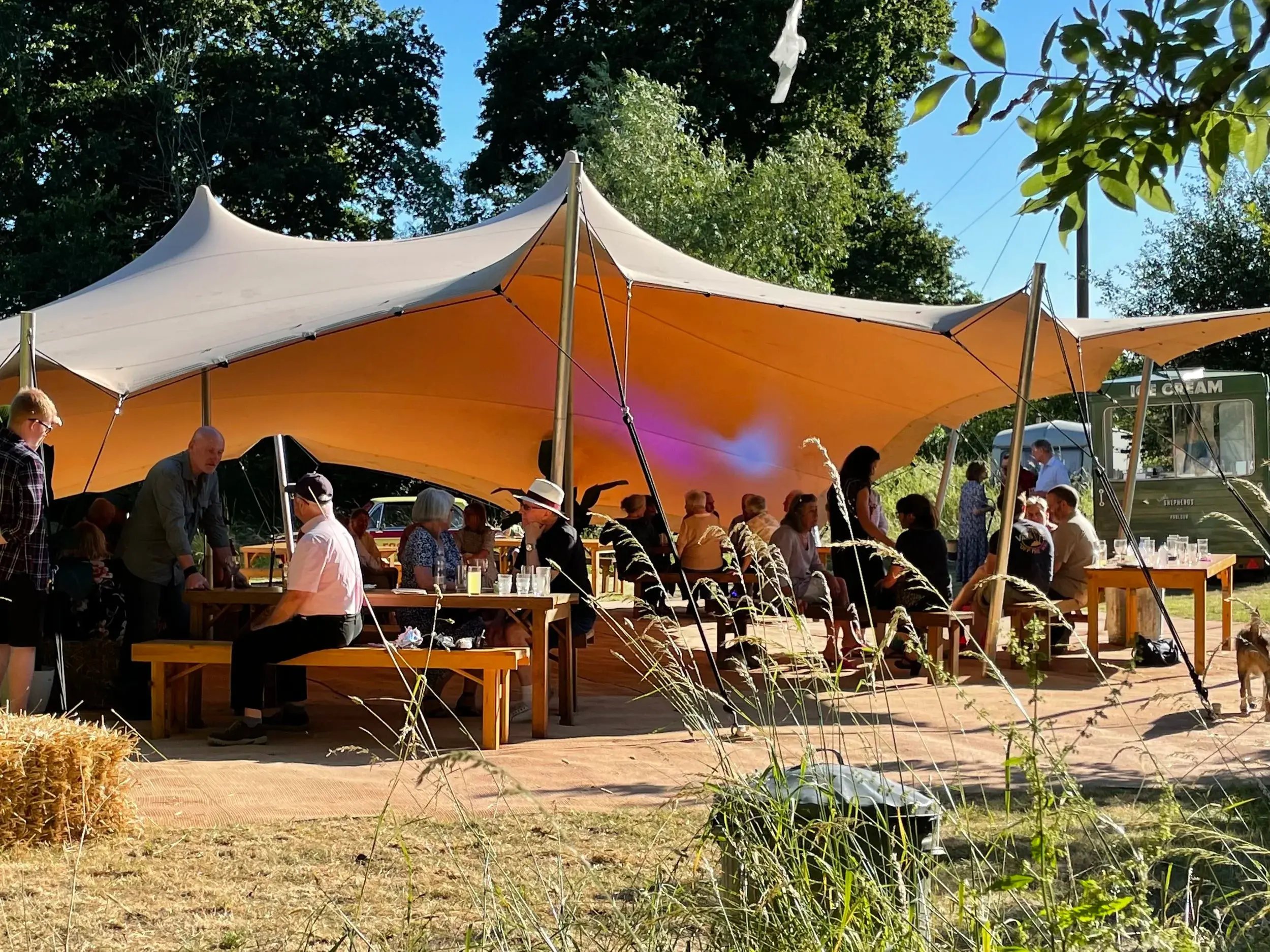 Sand-coloured stretch tent sheltering guests at long tables