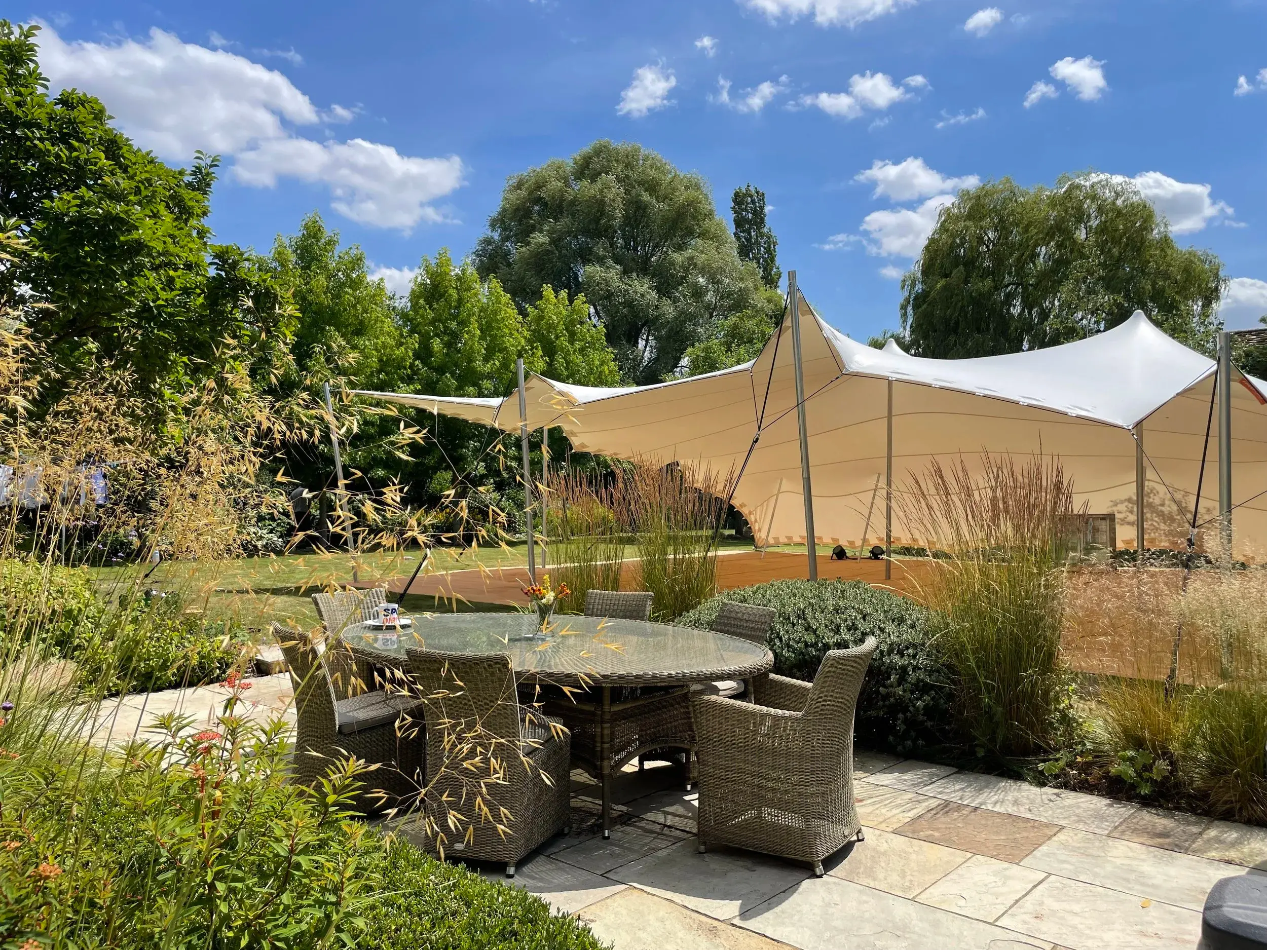 Stretch tent over a garden terrace with outdoor dining furniture